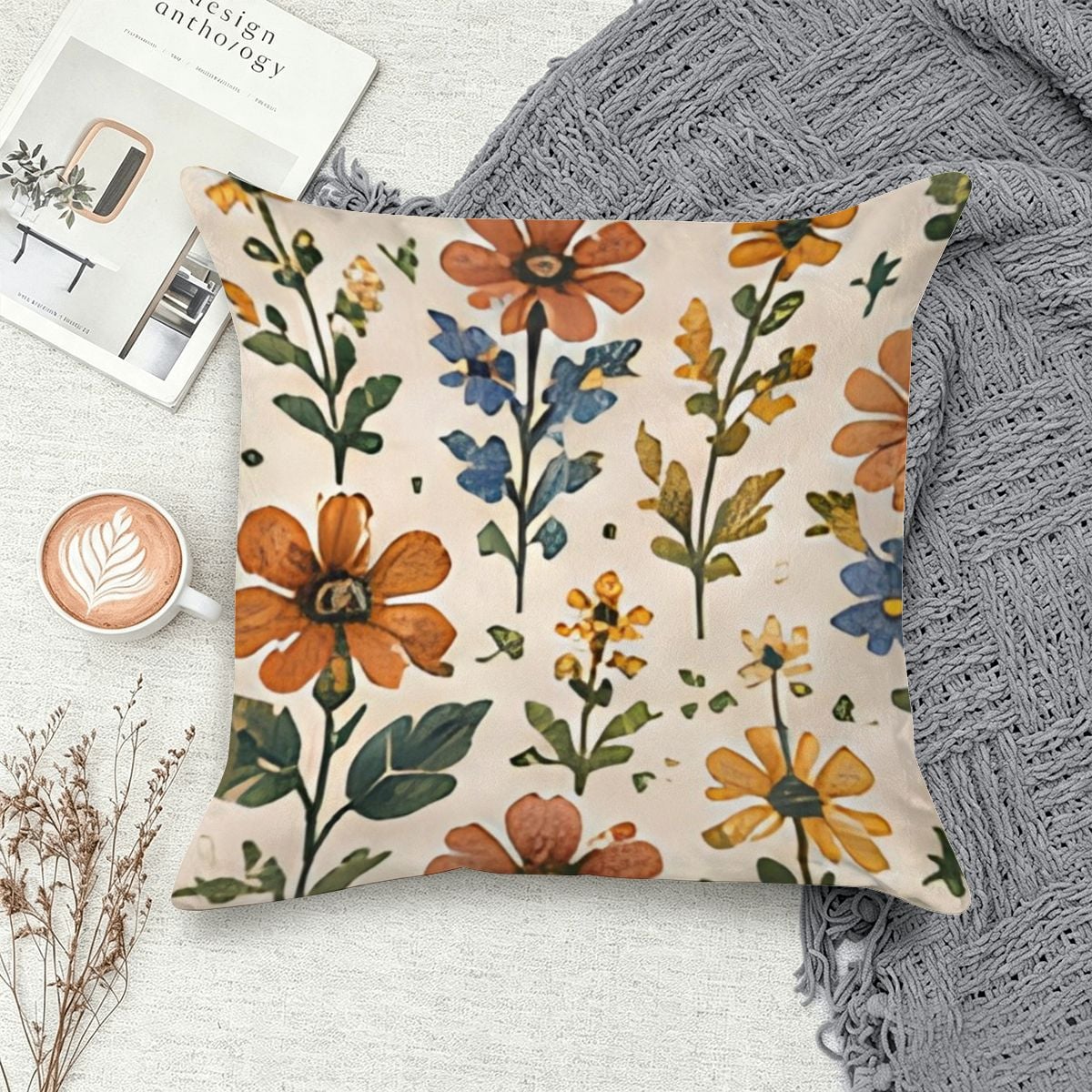 Floral patterned throw pillow with orange and blue wildflowers on a cream background.