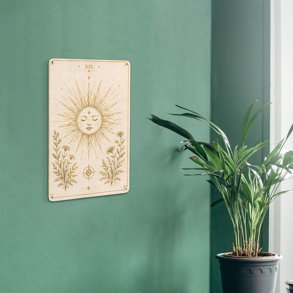 Celestial sun and floral botanical art print hanging on a green wall next to a potted plant.