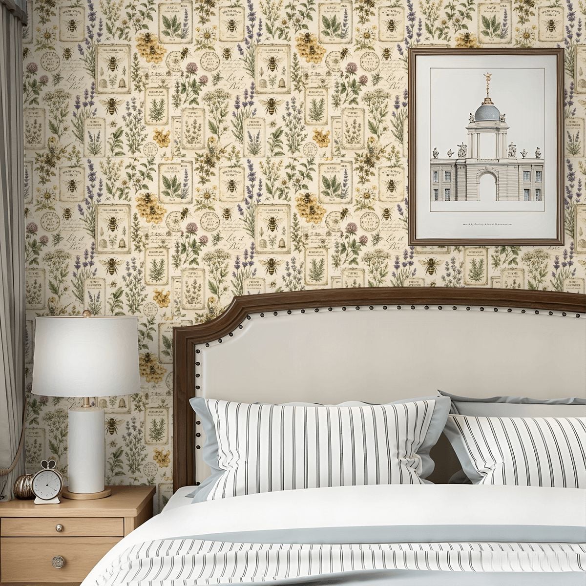 Botanical wildflower and bee pattern wallpaper in a bedroom with a white bed and lamp.