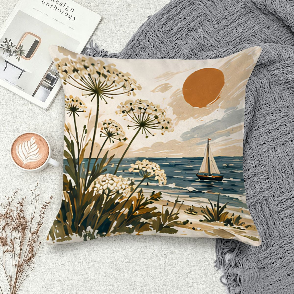 Coastal landscape throw pillow featuring white wildflowers, a sailboat, and a sunset over the ocean.