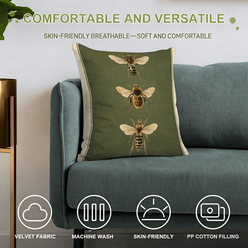 Green velvet throw pillow with vintage bee illustrations on a blue sofa.