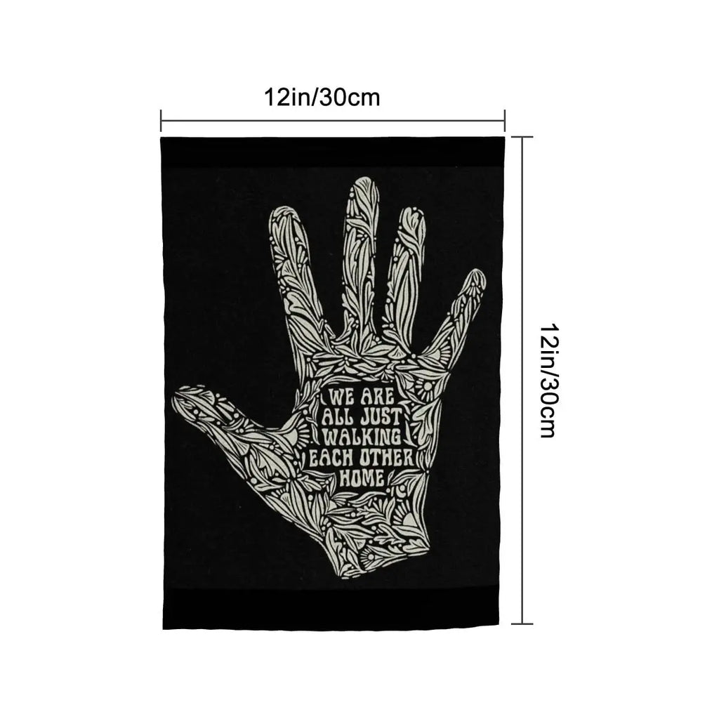 Sandy Beach garden decor flag with the message "We Are All Just Walking Each Other Home" displayed on a fabric flag in a garden setting.