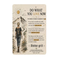 Inspirational metal sign featuring a woman walking towards mountains with motivational text.