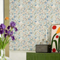 Seashell pattern wallpaper in blue and beige tones behind purple irises and a radio.