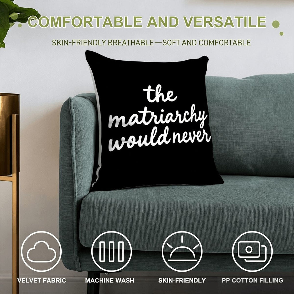 Black velvet decorative throw pillow with white text reading 'the matriarchy would never' on a sofa.