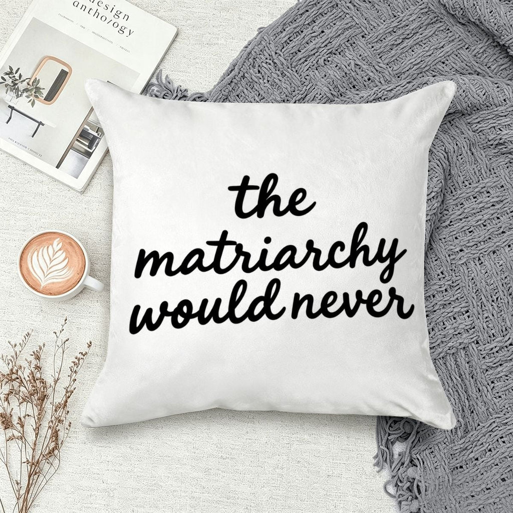 White decorative throw pillow with black text reading 'the matriarchy would never' on a cozy sofa.