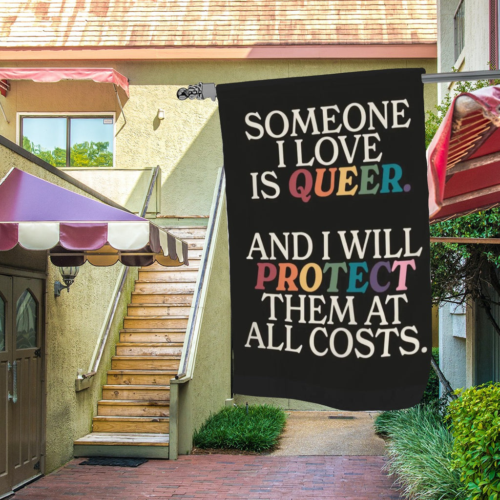 Colorful garden decor flag with "Someone I Love Is Queer" message, featuring floral design, by Sandy Beach for outdoor display