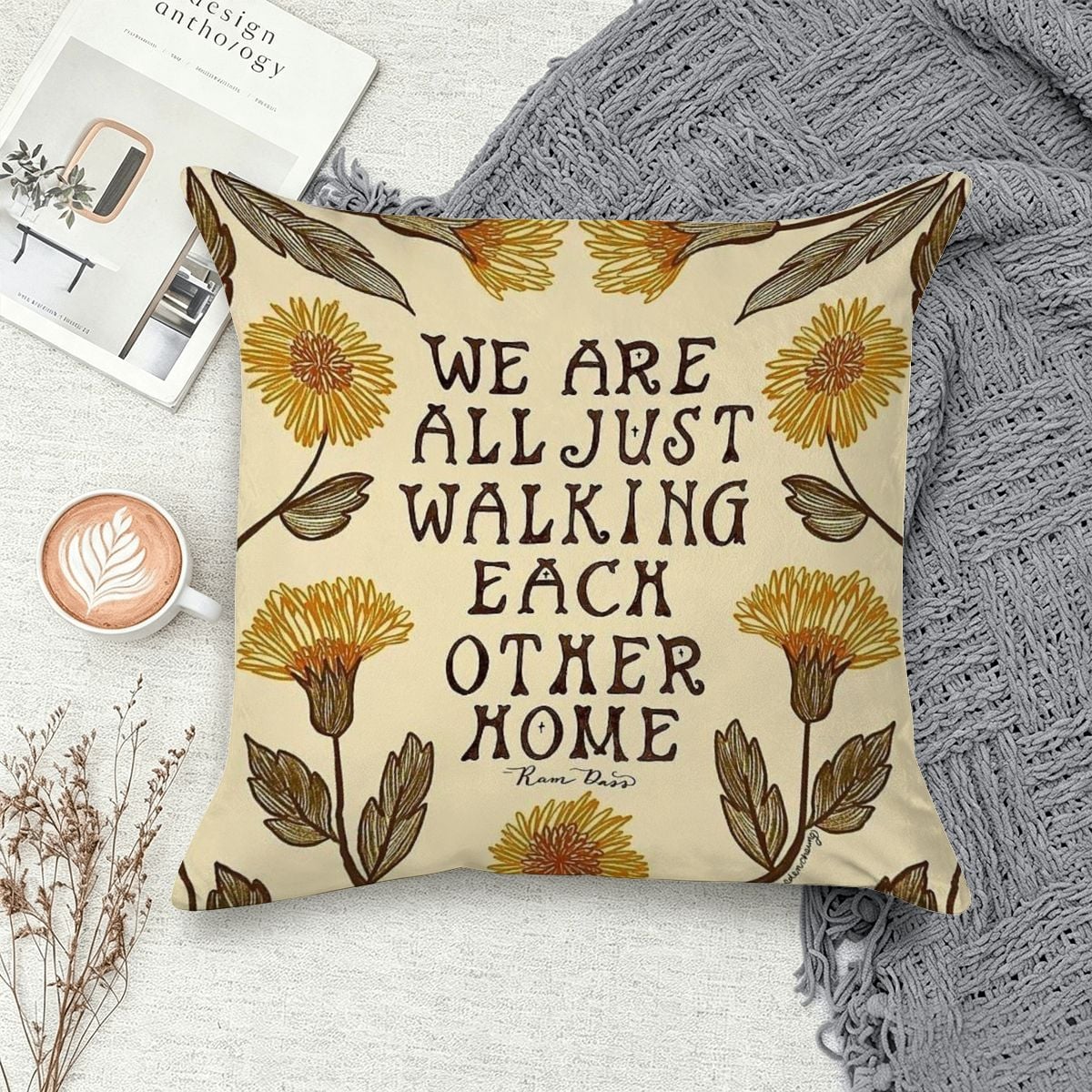 Decorative cream throw pillow with yellow floral patterns and Ram Dass quote.