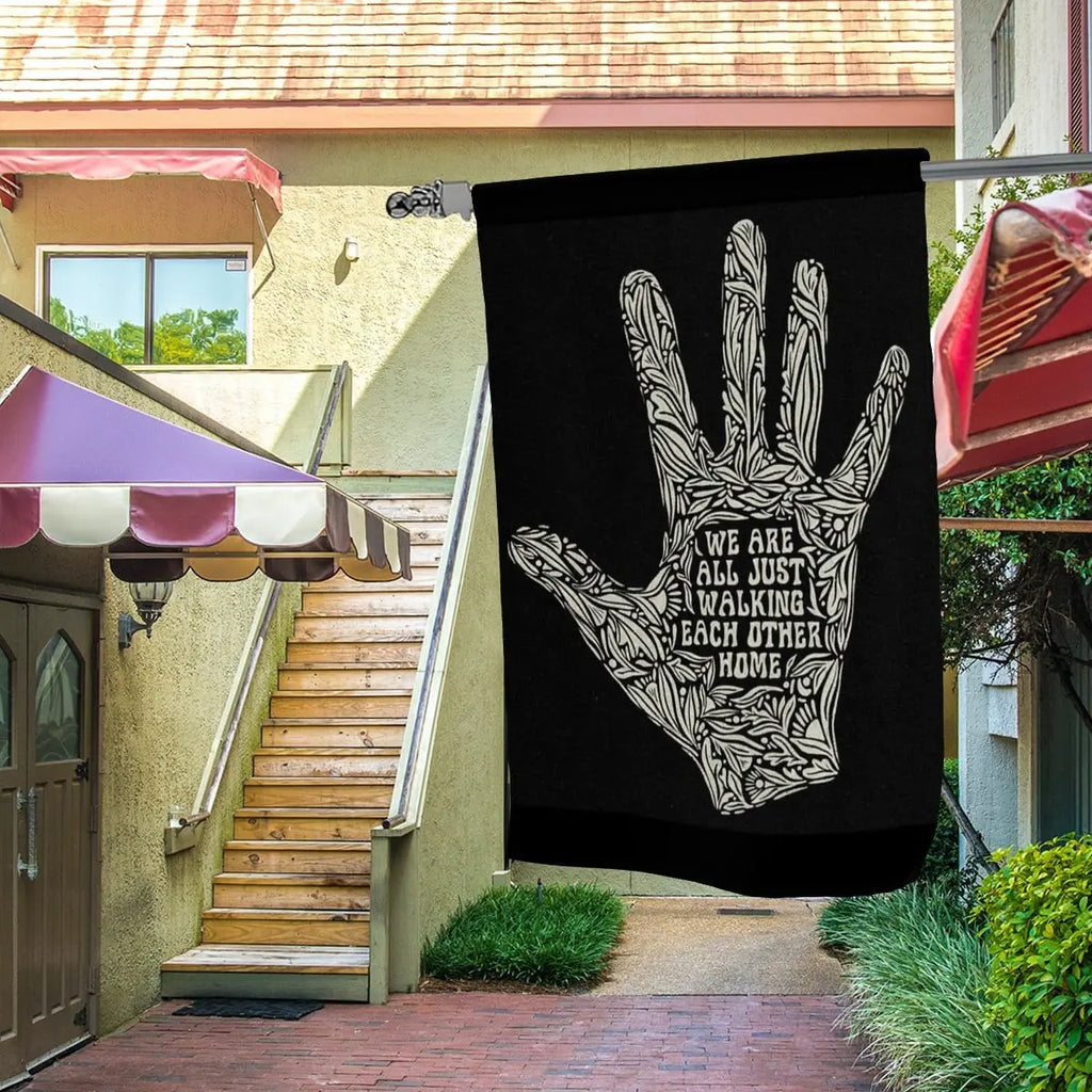 Sandy Beach garden decor flag featuring the message "We Are All Just Walking Each Other Home" with colorful design and outdoor display details.