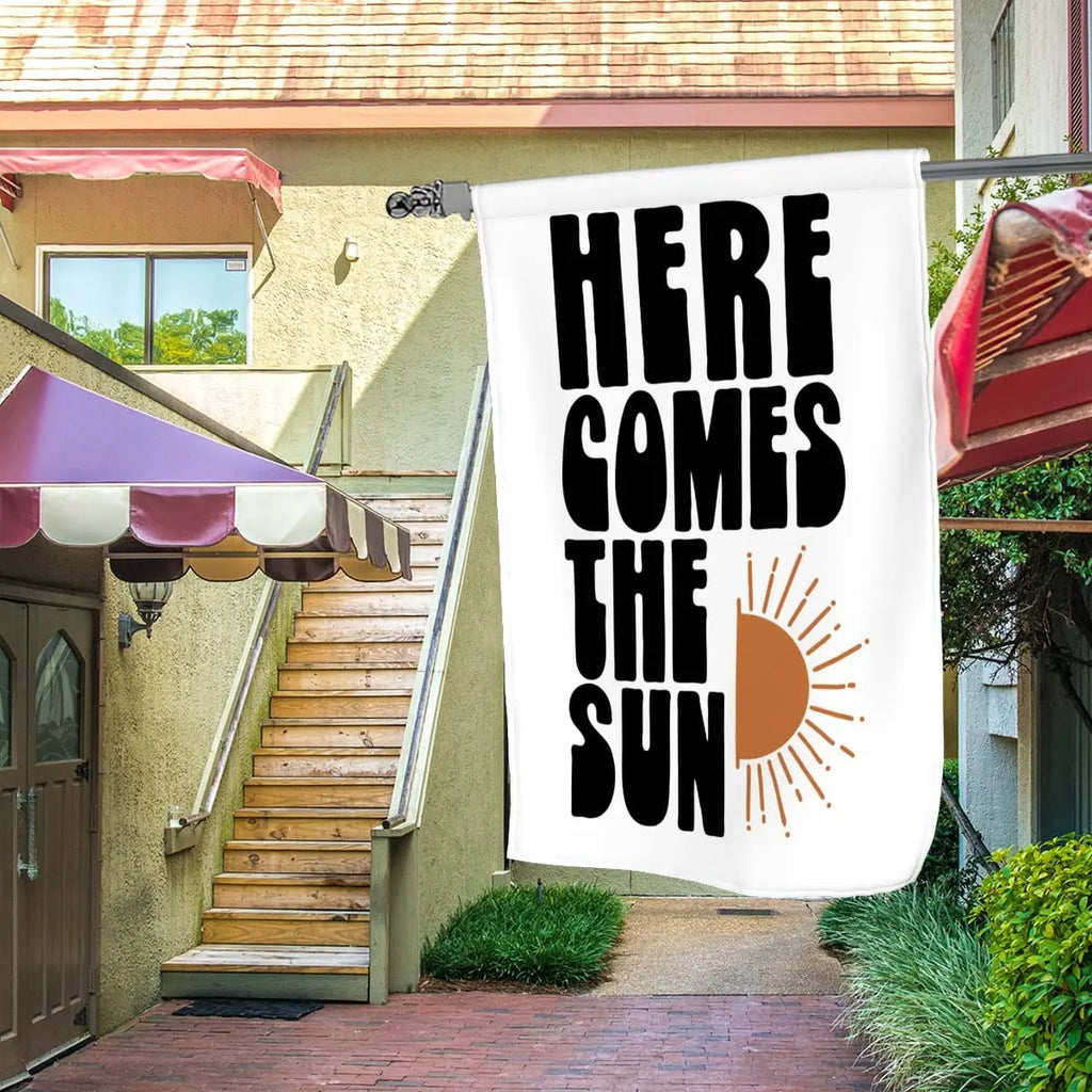 Sandy Beach Here Comes The Sun garden flag featuring bright sun and floral design for outdoor garden decor.