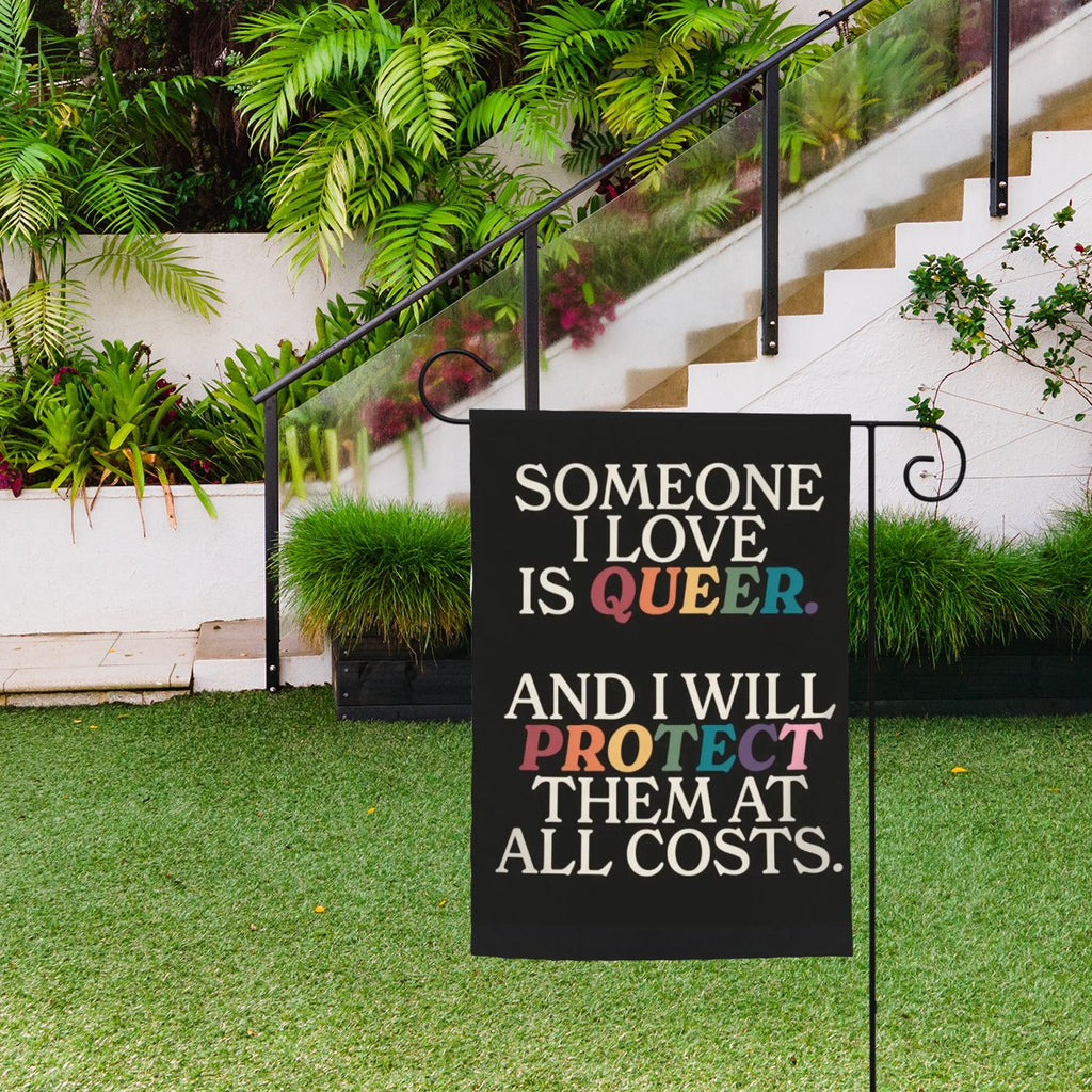 Sandy Beach garden decor flag with "Someone I Love Is Queer" message, featuring colorful floral design for outdoor display.