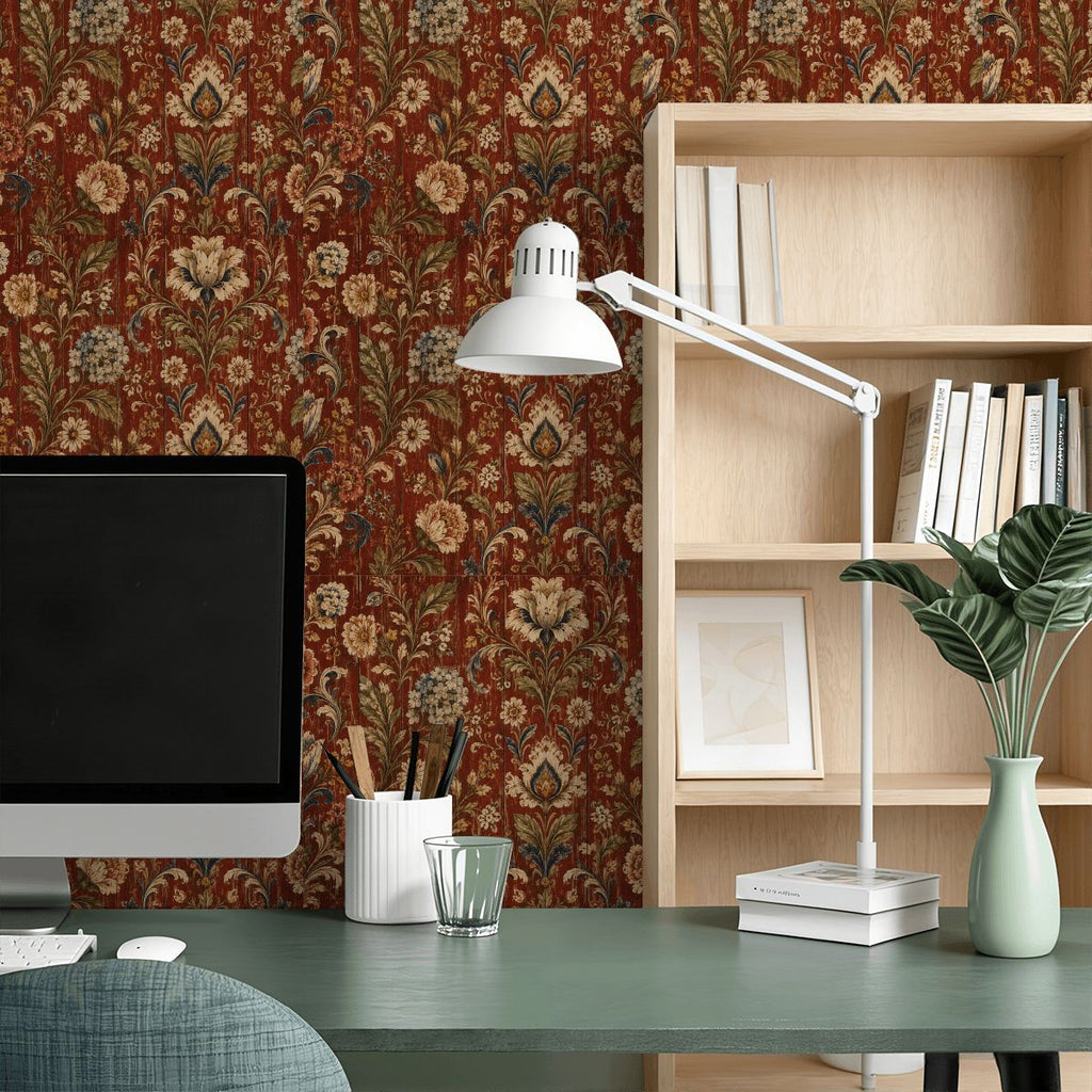 A desk setup featuring a computer monitor, white desk lamp, and books against floral patterned wallpaper.