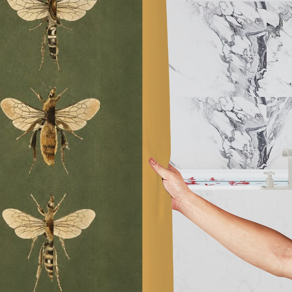 Hand holding a green shower curtain with vintage bee illustrations against marble tiles.